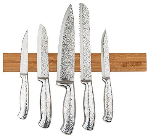 Bamboo magnetic knife strip holder mounted on a wall securely holding five stainless steel kitchen knives.