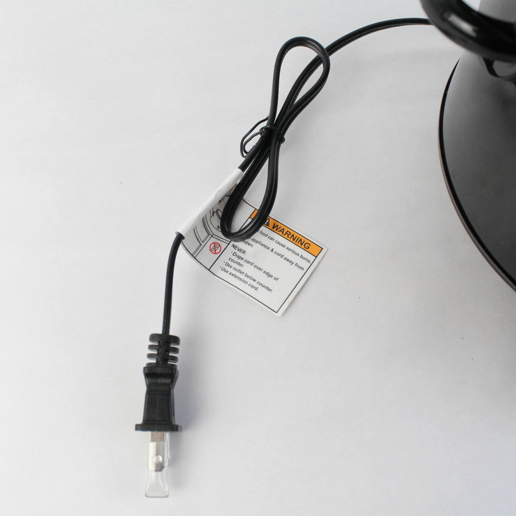 Close-up view of the black 2-prong power plug and attached safety warning tag for the Better Chef 3-quart slow cooker.
