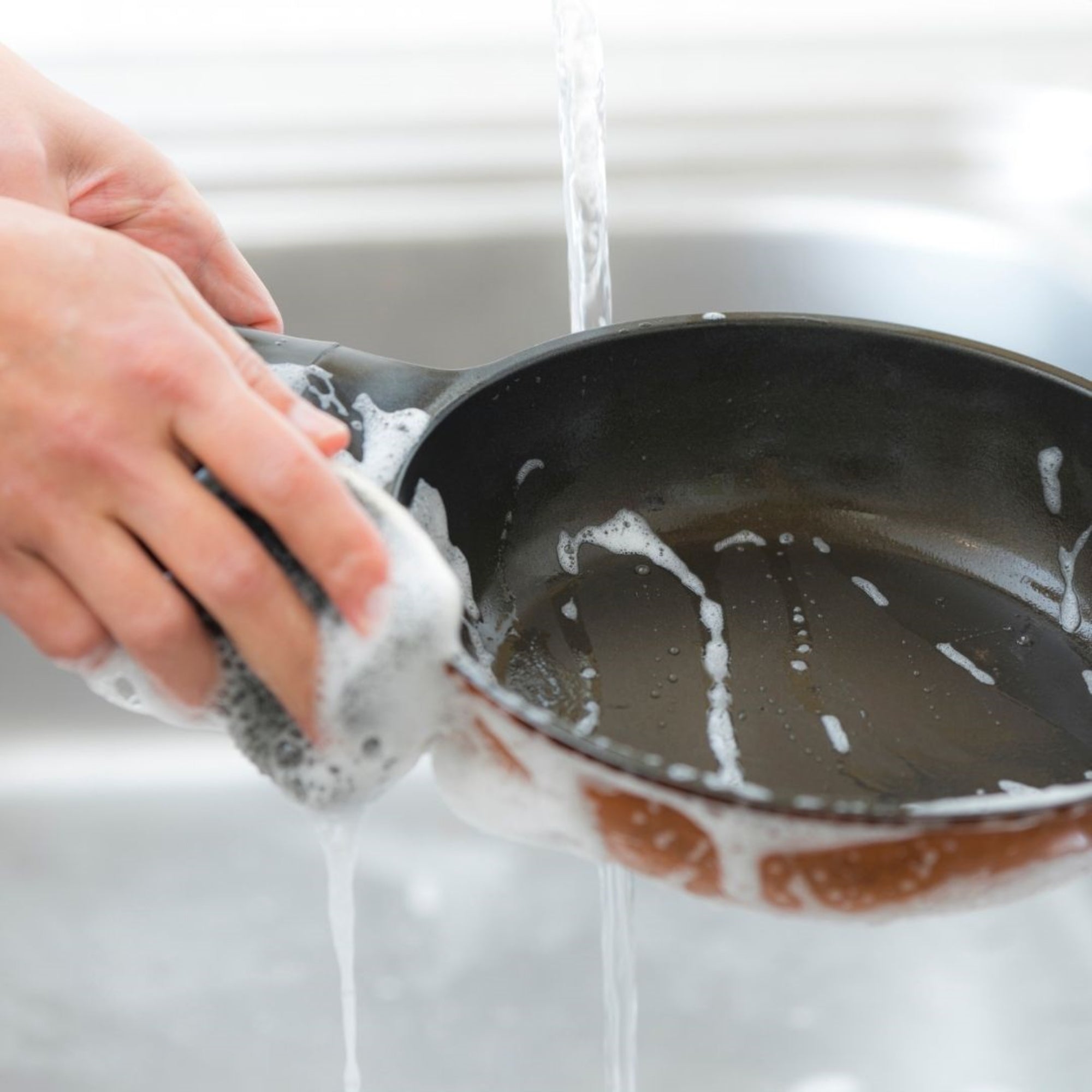 Hand washing the Cheftop nonstick frying pan under running water with soap, demonstrating the easy-clean surface.