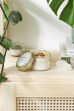 An open 4oz soy intention candle with a crackling wooden wick, sprinkled prosperity herbs, and a raw citrine crystal on a minimalist wooden display.