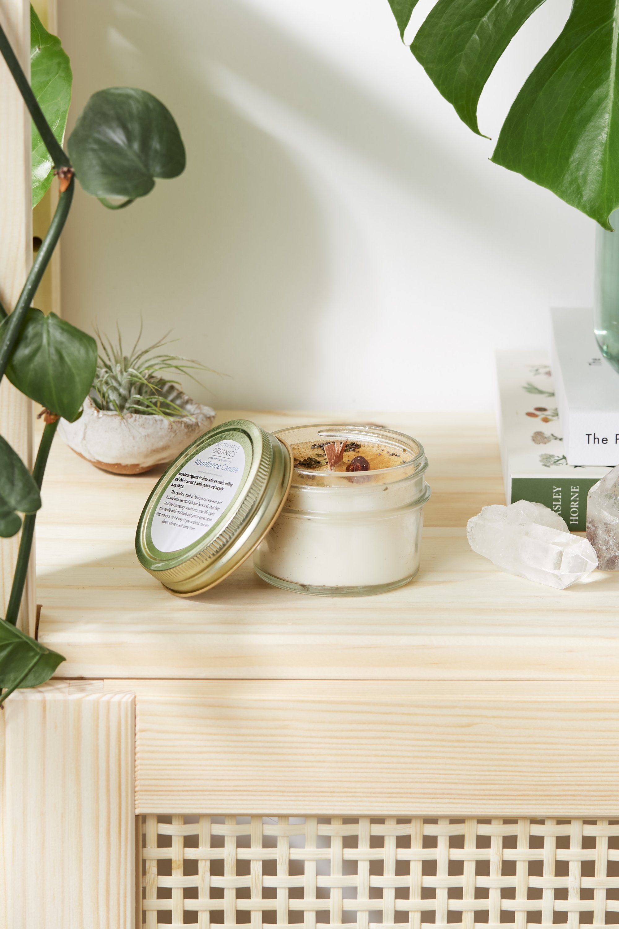 An open 4oz soy intention candle with a crackling wooden wick, sprinkled prosperity herbs, and a raw citrine crystal on a minimalist wooden display.