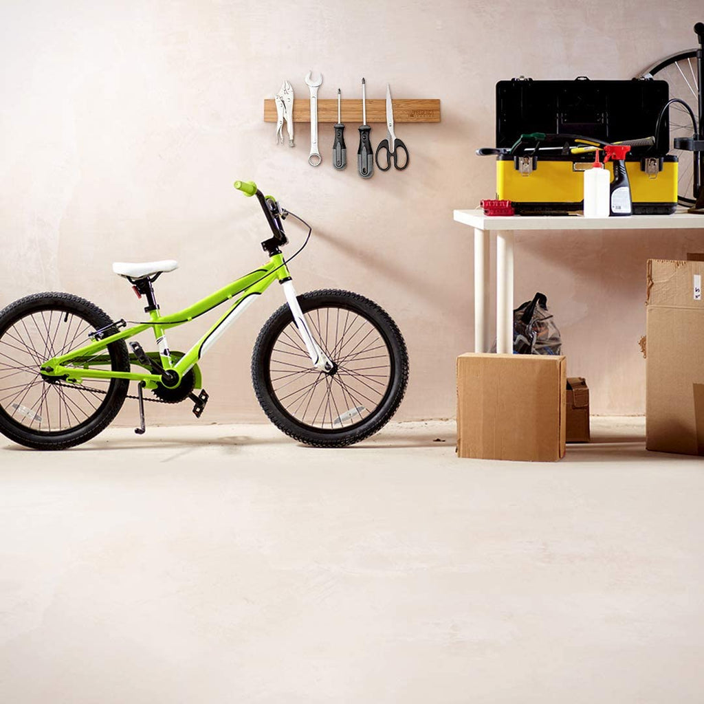 Wall mounted bamboo magnetic tool strip organizer holding hand tools in a home garage workshop next to a bicycle.