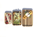 Top-down view of three nested rectangle acacia wood serving trays holding cheese, a green salad, and fresh berries.
