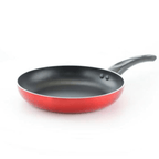 A metallic red nonstick frying pan with an ergonomic black handle heating chopped food on a lit gas stovetop burner.