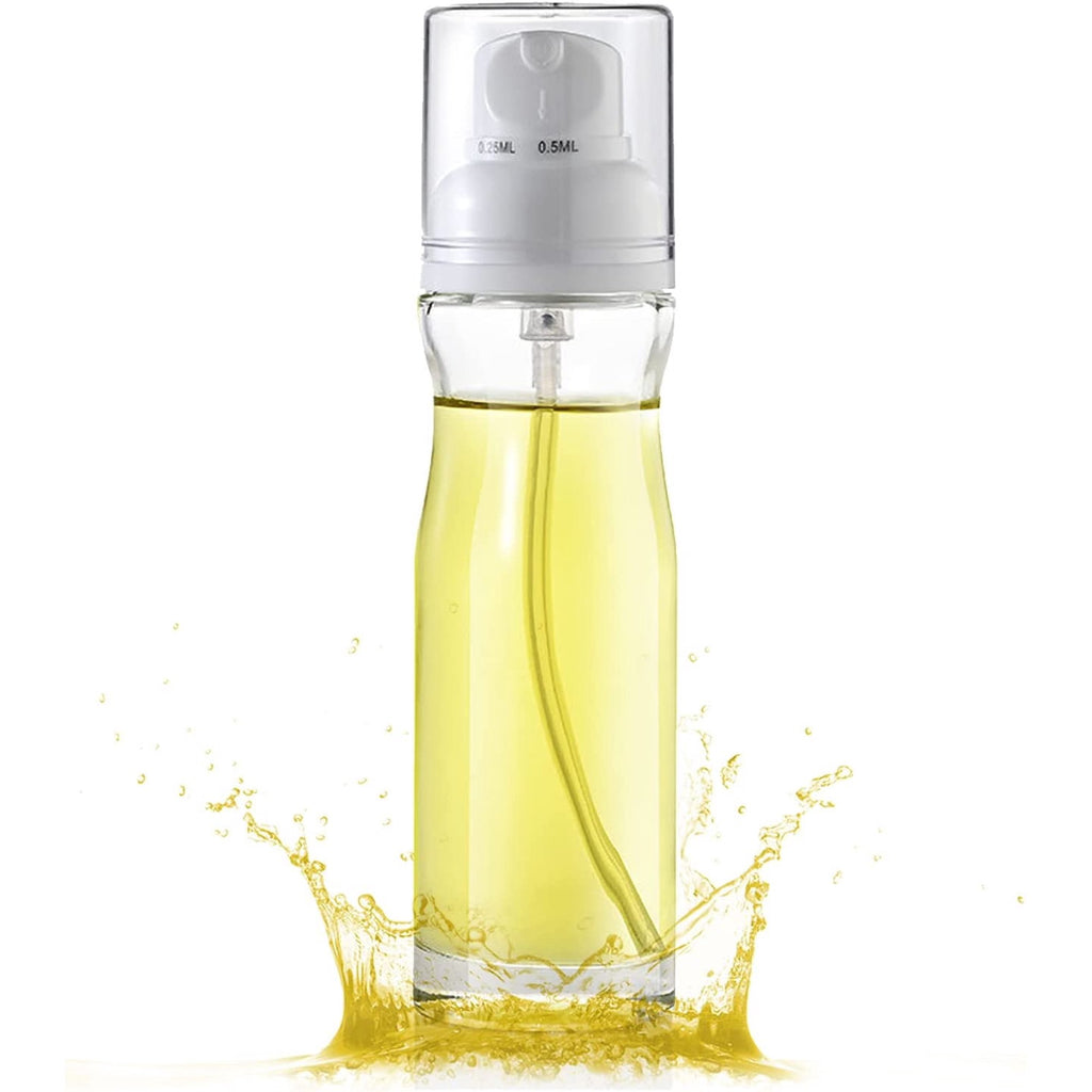 Reusable oil mister spraying fine mist over food to show air fryer cooking use.