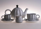 Sarka porcelain coffee and tea set featuring a teapot, milk jug, and two cups with saucers, decorated with black vertical stripes on a white background.